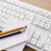 Teclado blanco con la tecla "Rediseñar" destacada, acompañado de hojas y lápices sobre el teclado, representando la reconstrucción institucional y el proceso de actualización de los estatutos de Fundación Equicentro en la Región del Maule.