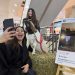 Una mujer sonríe y se toma una selfie junto al chivo Thor de Fundación Equicentro, el cual está posado sobre un fardo de paja en el Mall Portal Centro de Talca durante una feria regional.